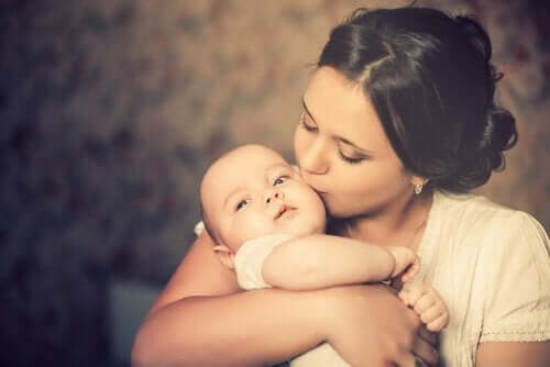 Kobieta całuje niemowlę w policzek