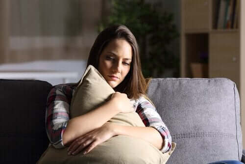 Kobieta siedzi na sofie i ściska poduszkę