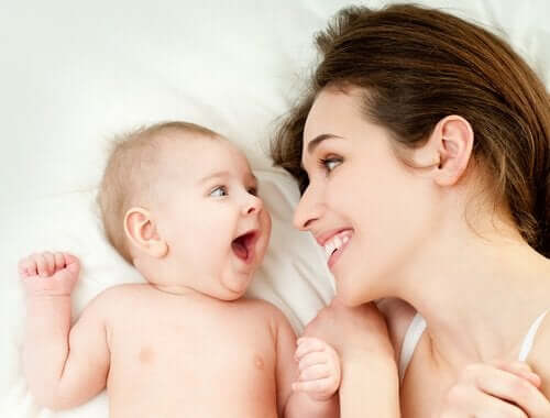 Matka i noworodek uśmiechają się do siebie szczęśliwi - więż dziecka z rodzicem