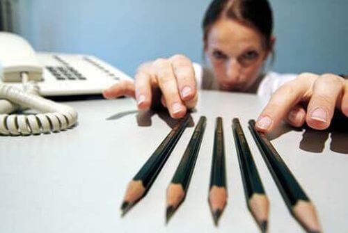 Kobieta pieczołowicie układa ołówki na biurku
