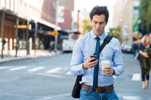 Smartfonowe zombie - mężczyzna patrzy na telefon, idąc ulicą