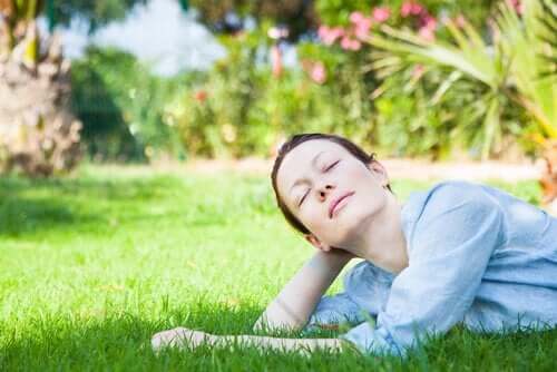 Kobieta odpoczywa z zamkniętymi oczyma na trawniku