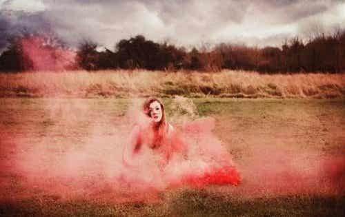 Kobieta otoczona różowym dymem na środku pola