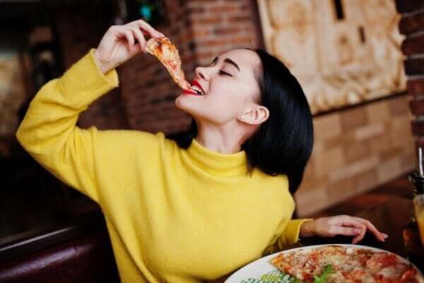 Kobieta je pizzę, jedną z czterech uzależniających potraw.